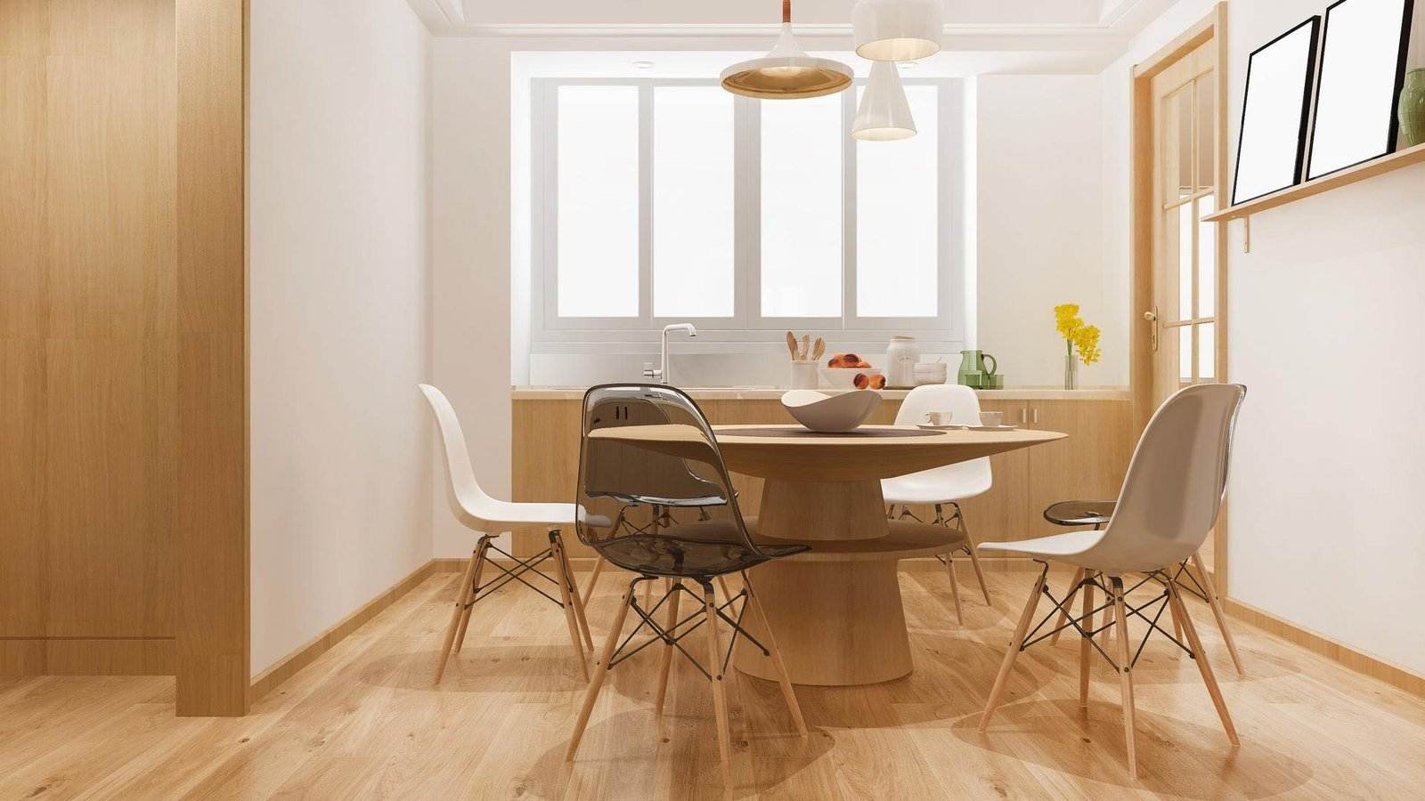 Ein moderner Essbereich mit einem runden Holztisch und vier Stühlen – zwei schwarzen und zwei weißen – ist eingerichtet. Der Raum ist mit hellem Holzboden und hellen Holzmöbeln ausgestattet. Darüber hängen drei Pendelleuchten. Ein Fenster mit Milchglas erhellt den Raum, daneben steht eine Vase mit gelben Blumen.